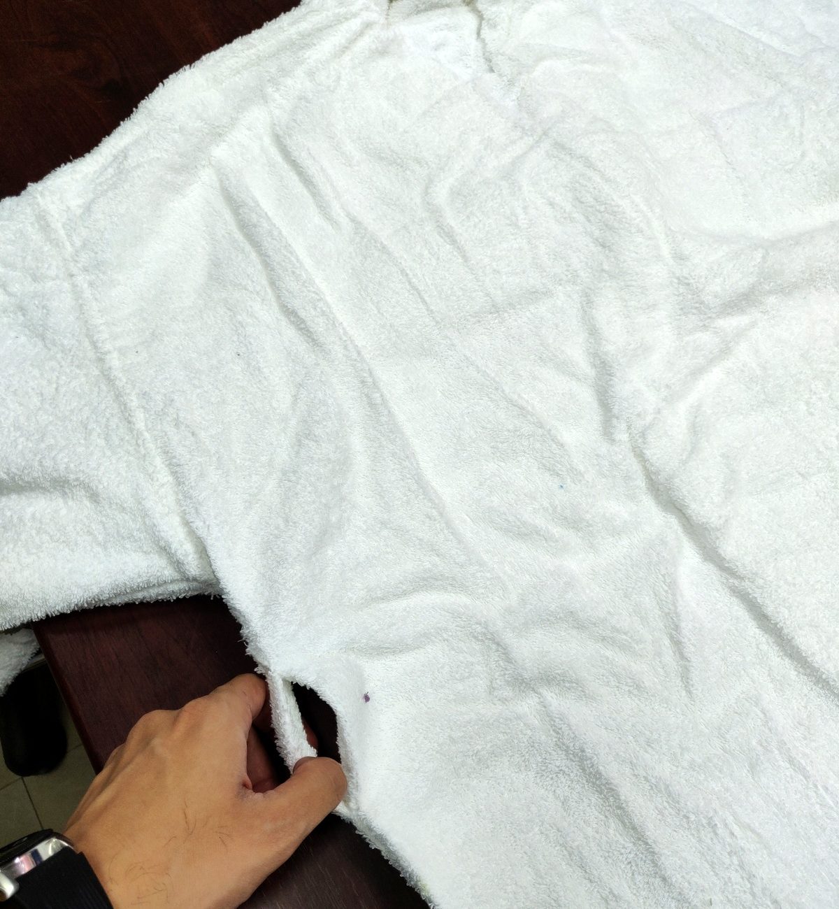 White terry bathrobe turned inside out, hand holding the side seam and belt loop